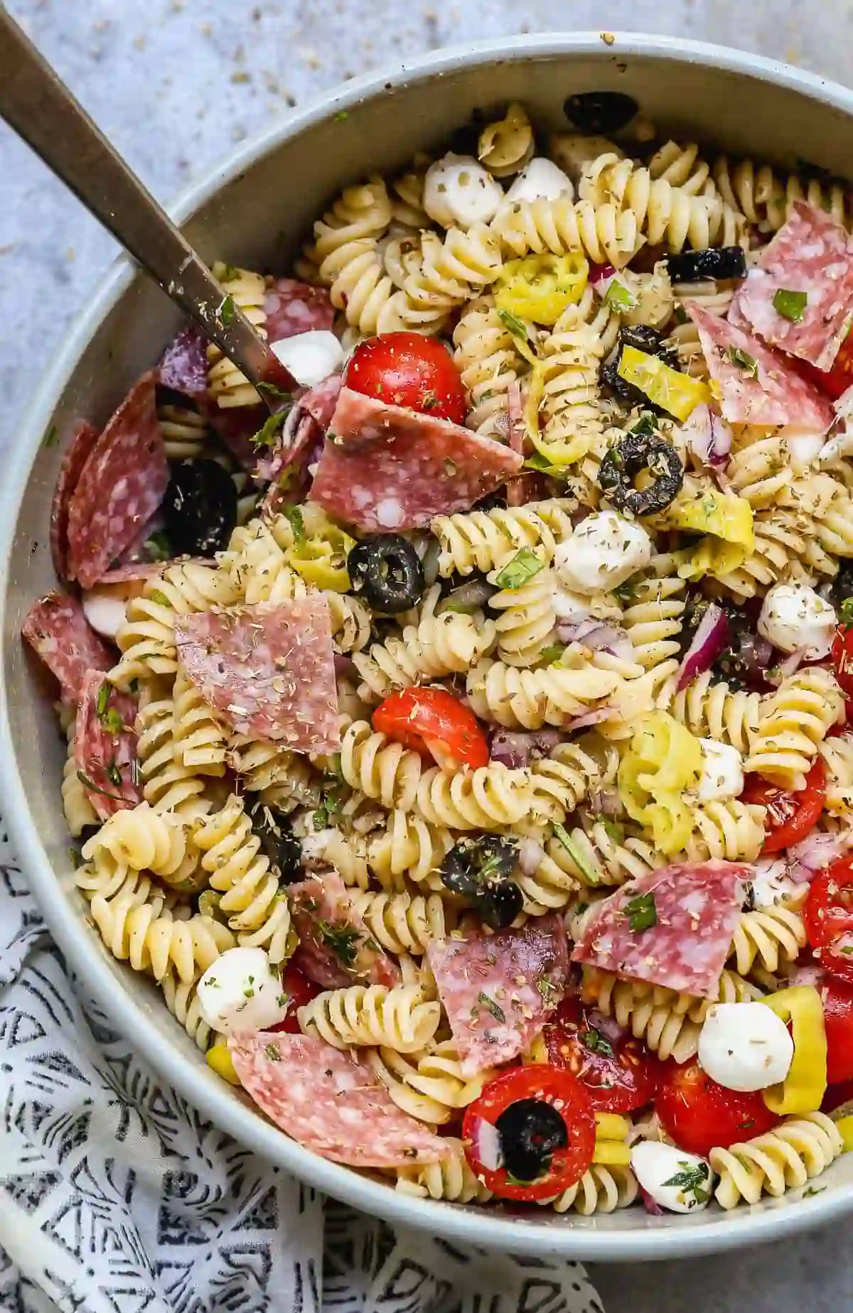 Italian pasta salad with salami, mozzarella, olives, cherry tomatoes, and herbs, served at an Italian restaurant near me